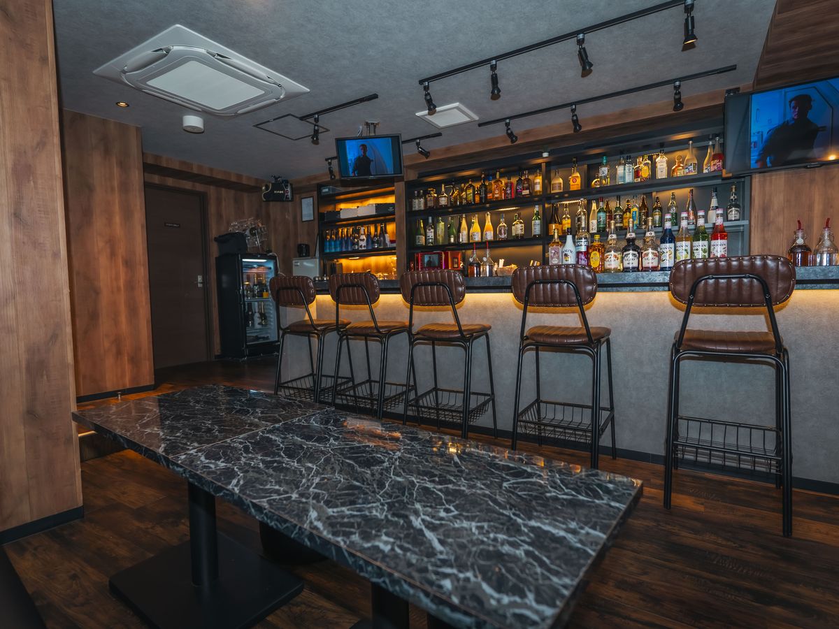 ウイスキーやリキュールがぎっしり並ぶBAR 1Carat 下北沢のバックバーと、手前の大理石調テーブル